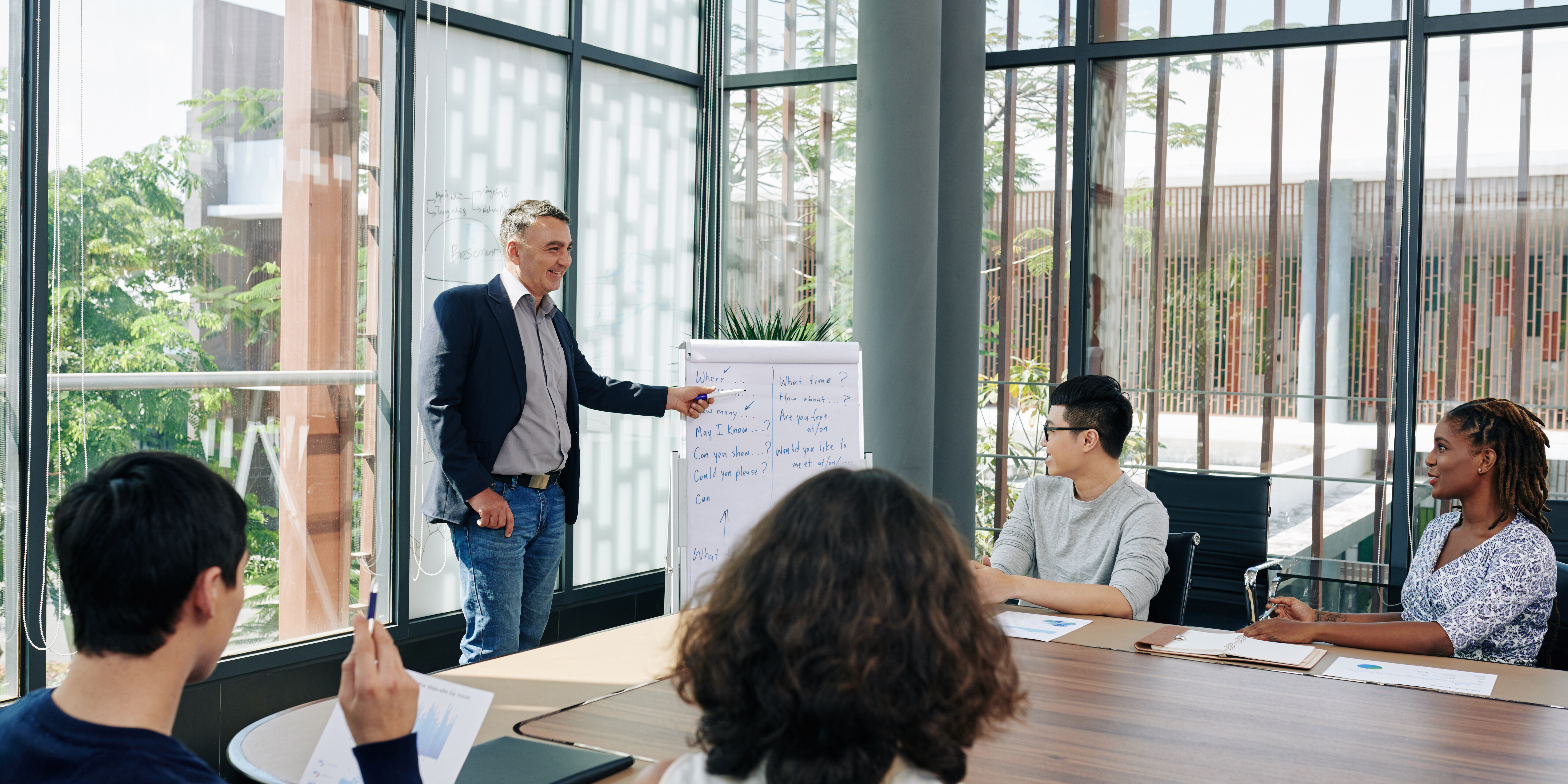 Smiling entrepreneur conducting training for entrepreneurs, explaining course and showing information on whiteboard